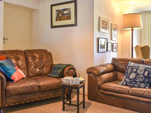 a living room with a brown leather couch and a table at Thornes Farm Annexe in West Quantoxhead