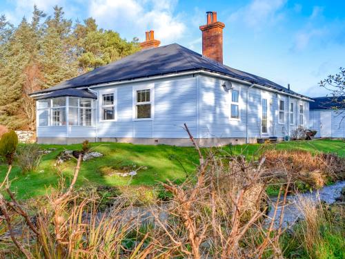 a white house with a chimney on top of a yard at Clarksburn Blue in Monreith