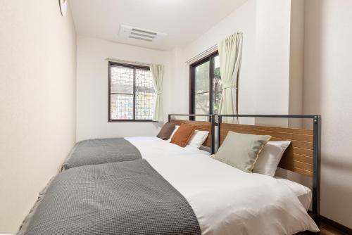a bedroom with two beds and two windows at -Numabukuro House- 10-minute walk from Numabukuro station in Tokyo