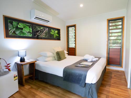 a bedroom with a bed and a table and a window at Safari Lodge in Cape Tribulation