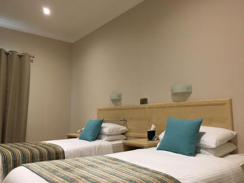 two beds in a hotel room with blue pillows at The Lodge Hotel in Coleraine