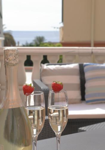 two wine glasses and a bottle of wine with strawberries in them at Albergo Belsoggiorno in Sanremo