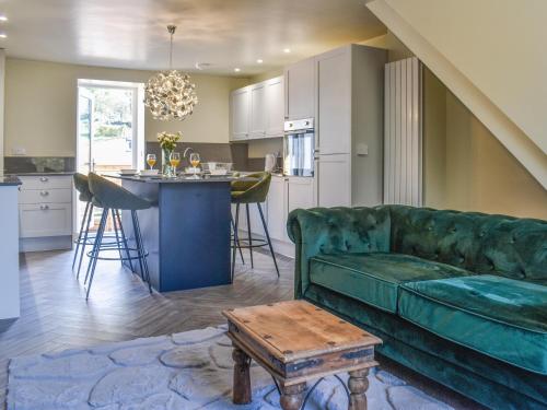 a living room with a green couch and a kitchen at Brun Cottage in Worsthorne