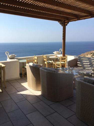 a patio with a table and chairs and the ocean at Hermes-Ios Rooms To Let in Ios Chora
