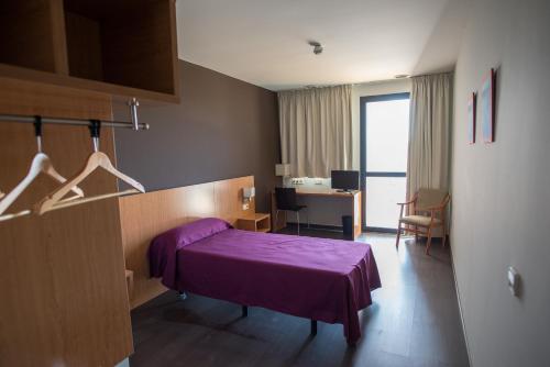 Habitación de hotel con cama morada y escritorio. en Hostal Mediterranea, en Madrid