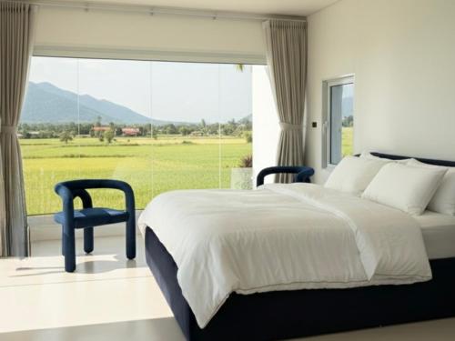 a bedroom with a large bed and a large window at MITI TIKAAN villa in Ban Muang Chum