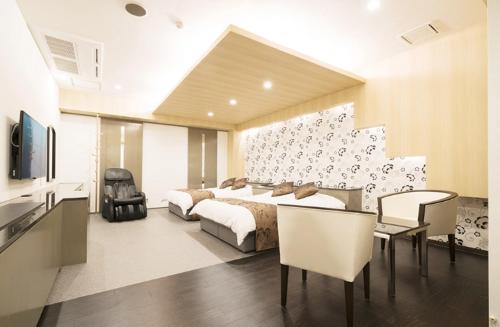 a bedroom with two beds and a table and chairs at Hotel Revoir in Izumi