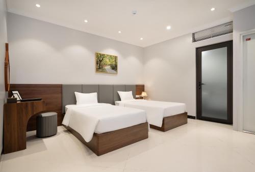 ein Schlafzimmer mit zwei Betten und einem Schreibtisch in der Unterkunft Diamond Light Hotel in Hanoi