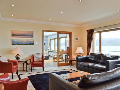 a living room with a leather couch and chairs at Waterside in Tighnabruaich
