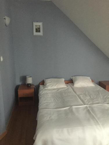 a bed with white sheets and pillows in a bedroom at Zajazd Zachęta in Kamienna Góra