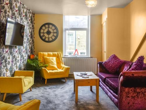 a living room with yellow and purple furniture at Hollingreave House in Burnley