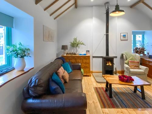 a living room with a leather couch and a fireplace at No2 The Neuk in Belford