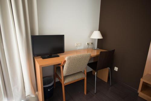 Habitación con escritorio, TV y silla. en Hostal Mediterranea, en Madrid
