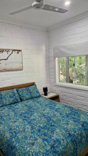 a bedroom with a bed with a blue comforter and a window at Quiet Country Retreat in Forster