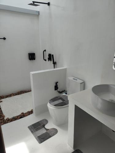 a white bathroom with a toilet and a sink at Salt Serenity in Thoddoo