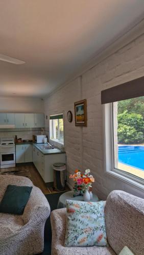 a living room with a couch and a table and a kitchen at Quiet Country Retreat in Forster