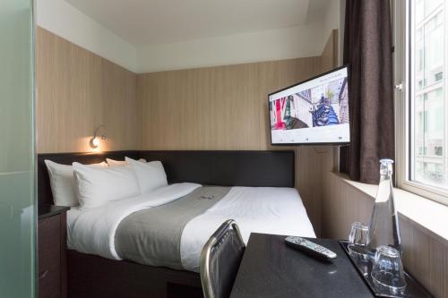 a hotel room with a bed and a flat screen tv at The Z Hotel Victoria in London