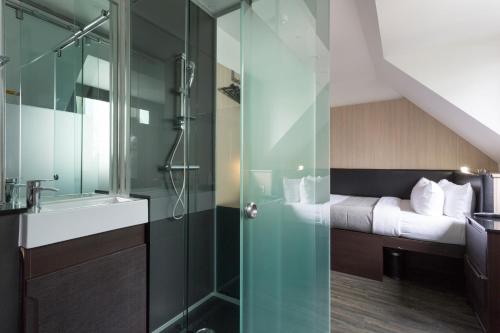 a bathroom with a glass shower with a bed at The Z Hotel Victoria in London