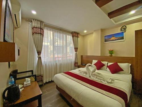 a hotel room with a bed with swans on it at Hotel Maheshwor in Pashupatināth