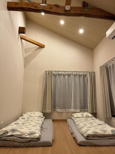 two beds in a room with a window at shine house warabi2 in Warabi