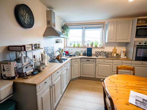 a kitchen with white cabinets and a table and a window at Appartement Spa VIP du Pont Alsort 2-3 in Froid-Chapelle