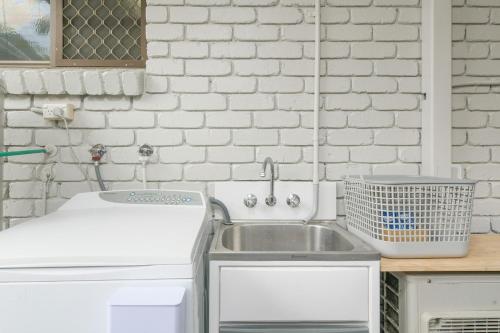 a kitchen with a sink and a white brick wall at Hidden Gem - 3BR Home - Cairns in Edge Hill