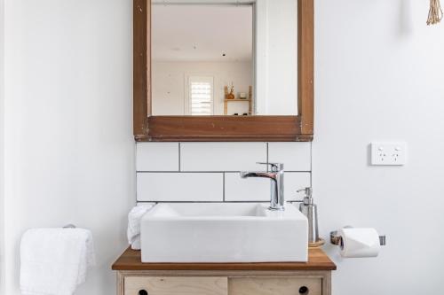 a bathroom with a sink and a mirror at Walnut Studio in Raglan