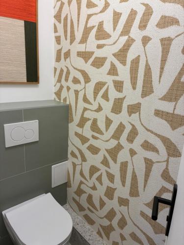 a bathroom with a toilet and a patterned wall at Chez nous Mulhouse - Hyper Centre - Parking - Balcon - Netflix in Mulhouse