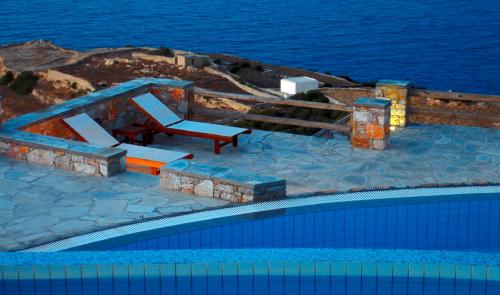 a swimming pool with a chair next to the ocean at Miramare Hotel in Chora Folegandros