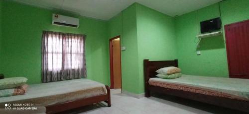 a green room with two beds and a window at Bayu Beach Chalet PCB in Kota Bharu