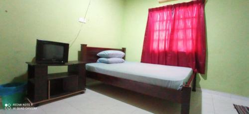 a bedroom with a bed with a red curtain and a tv at Bayu Beach Chalet PCB in Kota Bharu