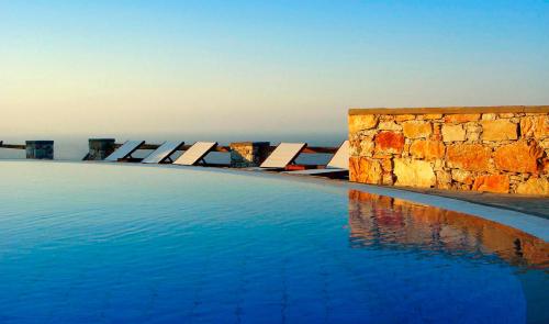 a swimming pool with chairs in the water at Miramare Hotel in Chora Folegandros