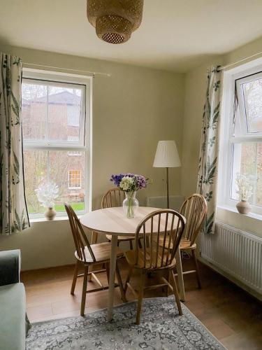 a dining room with a table and chairs and two windows at Cozy flat in King's Lynn