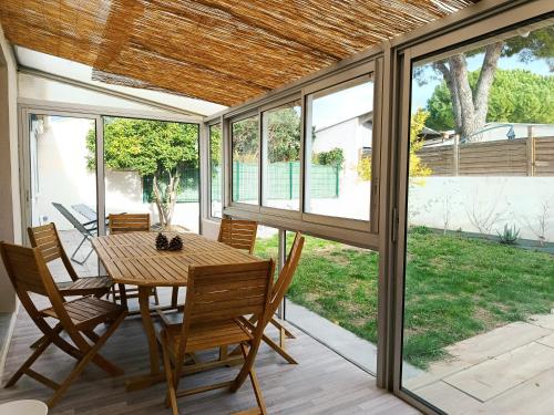 Maison Liloute في ميزيه: غرفة طعام بها طاولة وكراسي ونوافذ