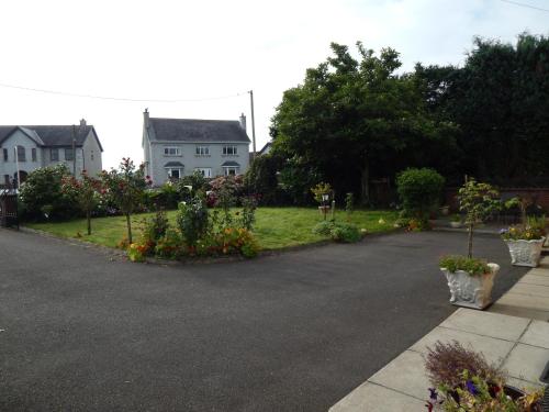 a driveway with flowering plants and a house at Scapaflow B&B in OʼBriensbridge