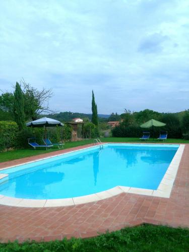 a large blue swimming pool with chairs and umbrellas at Casa ai Carfini in Poggibonsi