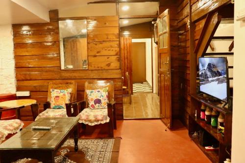a living room with wooden walls and chairs and a television at DI Heritage in Kodaikānāl
