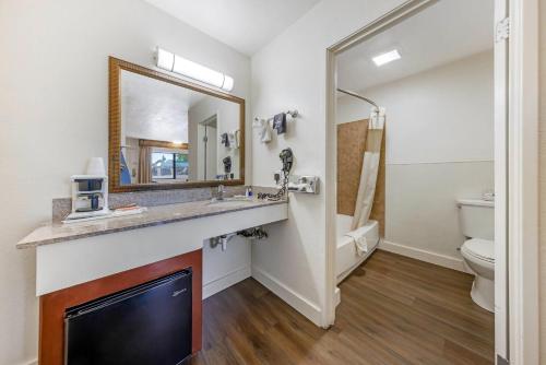 a bathroom with a sink and a toilet and a mirror at Rodeway Inn at Nevada State Capitol in Carson City