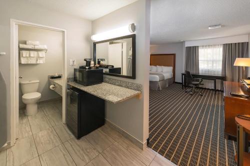 a hotel room with a bathroom with a sink and a toilet at Clarion Pointe Medicine Hat Saamis Tepee in Medicine Hat