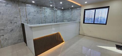 a bathroom with a glass shower with a window at Hotel Empire in Vapi