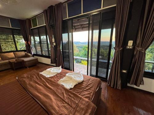 a bedroom with a bed and a large window at Wanwan Lanna By Pat in Ban Huai Thong