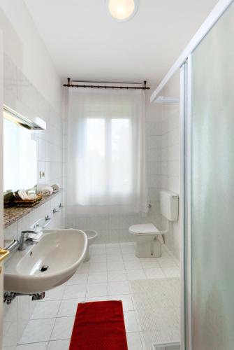 a white bathroom with a sink and a toilet at Hotel Columbia Terme in Abano Terme