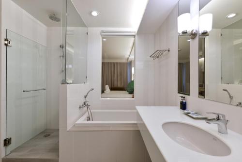 a white bathroom with a sink and a shower at Hisea Huahin Hotel in Hua Hin
