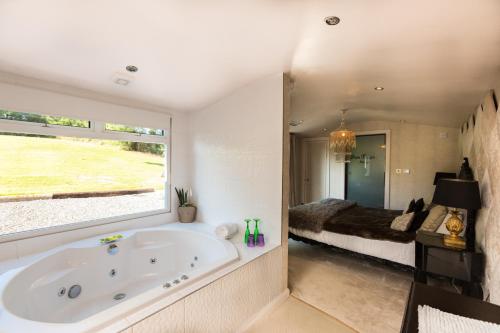 a bathroom with a tub and a bedroom with a bed at Who'd A Thought It in Lenham
