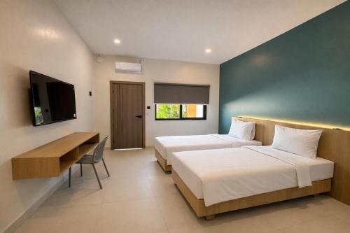 two beds in a room with a desk and a tv at Bene Residence in Maluk