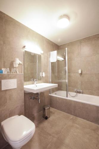 a bathroom with a toilet and a sink and a tub at Hotel Lepelbed in Ghent