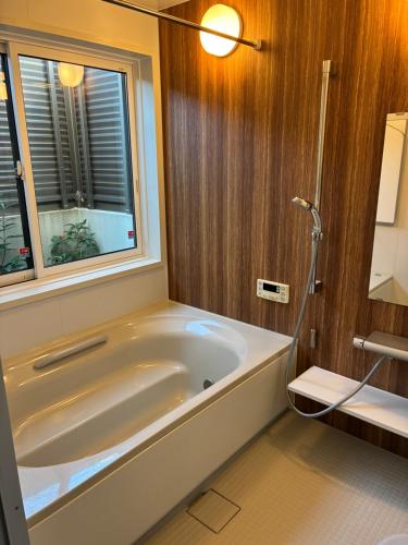 a bathroom with a tub and a window at Aoshima Seaside Village in Miyazaki