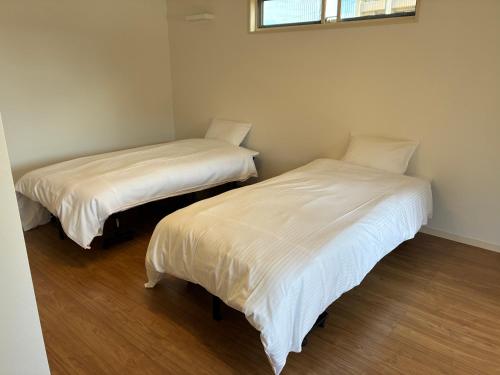 two beds in a room with white sheets at Aoshima Seaside Village in Miyazaki