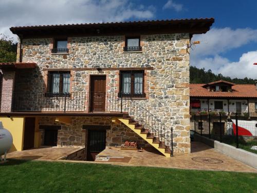 a stone house with a staircase in front of it at La Casuca in Rasines