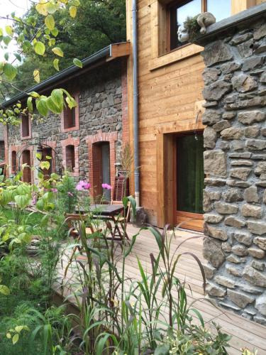 un patio con mesa y un edificio de piedra en Les Sittelles de Bamboche, en Saint-Symphorien-sur-Coise